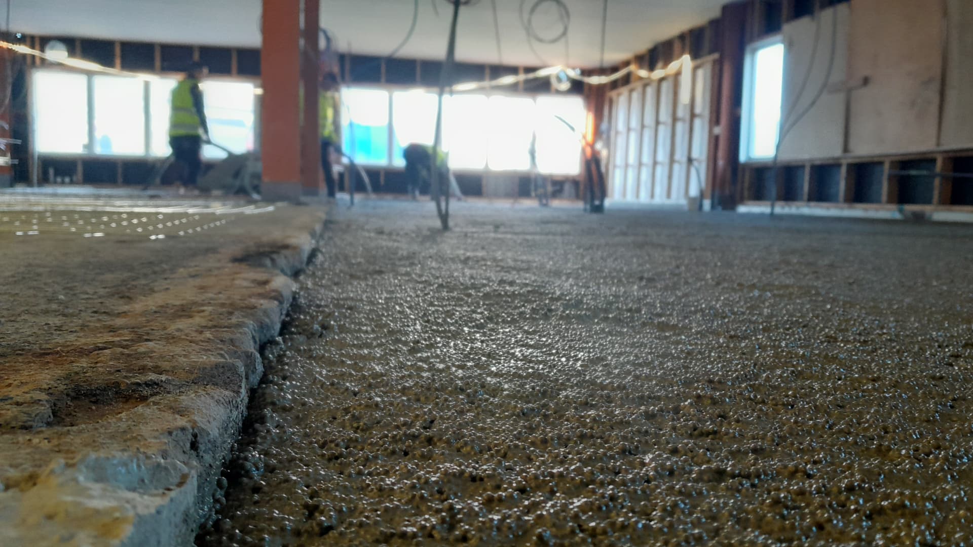 EPS-cement being pumped over underfloor heating pipes inside a building