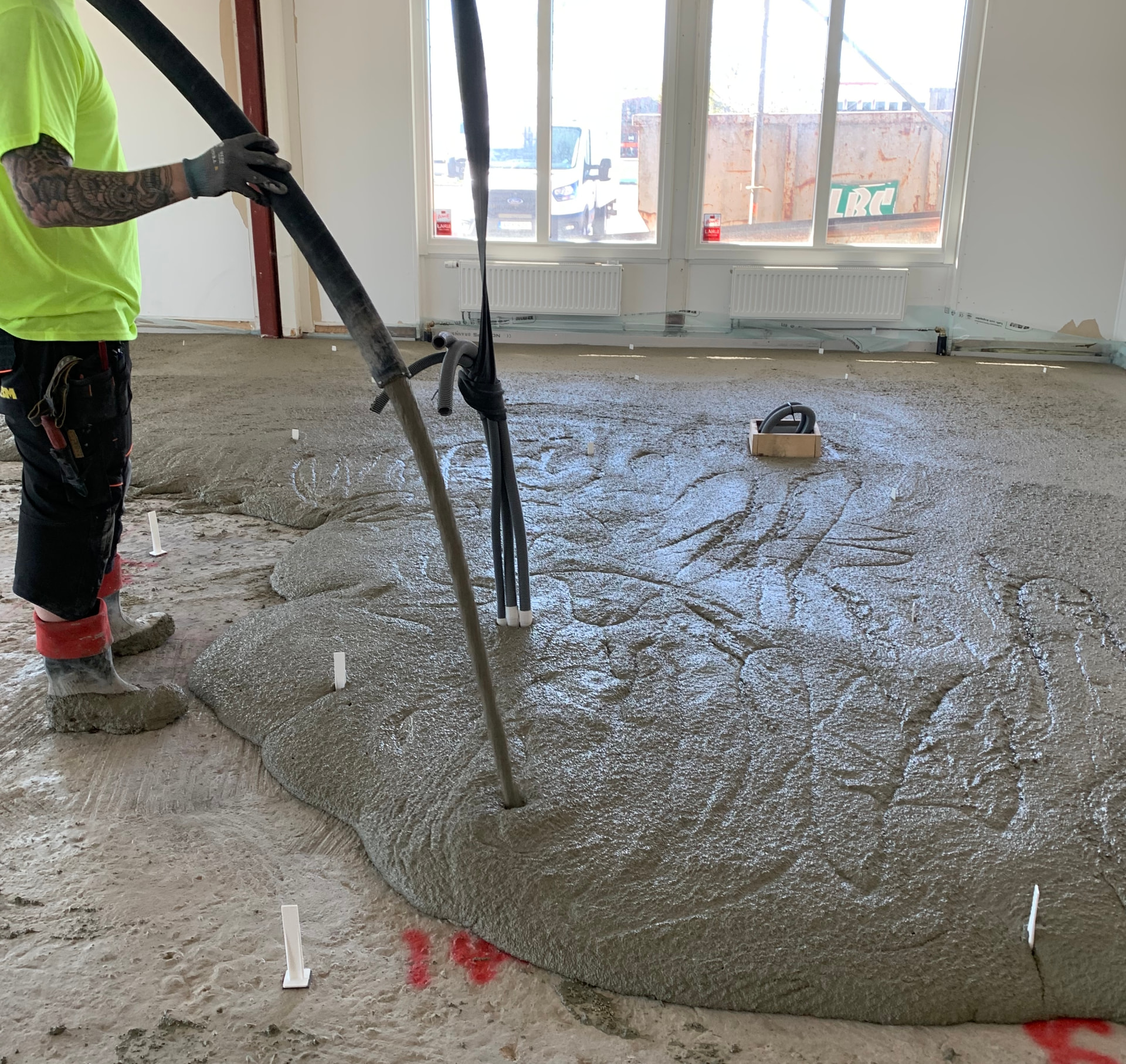EPS-cement being pumped over underfloor heating pipes inside a building